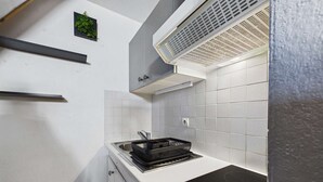 A compact kitchen with a built-in stove, a sink, and a small countertop. - Charming Studio with Mezzanine & Terrace for 6 in Marseillan, Parking Included (Marseillan-Plage)