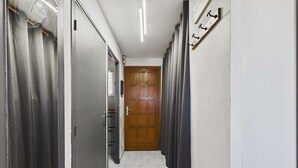 A hallway with a wooden door, metal lockers, and a coat rack. - Charming Studio with Mezzanine & Terrace for 6 in Marseillan, Parking Included (Marseillan-Plage)
