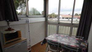 Une petite cuisine équipée d’un four à micro-ondes, une table avec des chaises et une vue dégagée grâce à de grandes fenêtres.