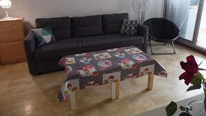 Un salon avec un canapé, une table basse, un ventilateur, un fauteuil et une rose.