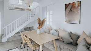 A modern interior with a wooden dining table, a sofa, and a staircase. - MyMykonos Villa II beachhouse  (greece)