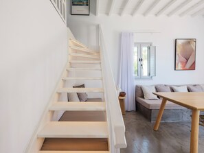 Un escalier avec des rampes blanches menant à un espace de vie comprenant un canapé et une table.