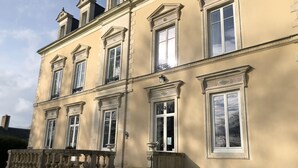 Un bâtiment de style classique, doté de nombreuses fenêtres et d’une balustrade en pierre.
