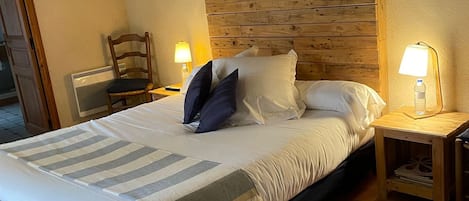 A hotel room with a bed, a chair, a nightstand with a lamp, and a picture on the wall.