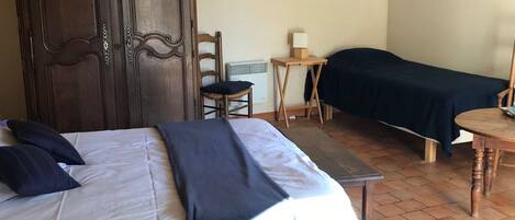 Een slaapkamer met een bed, een stoel, een klein tafeltje en een kledingkast.
