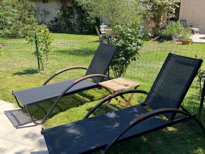 A garden with two lounge chairs and a small wooden table. - Countryside Retreat with Pool Near Solesmes Abbey (Solesmes)