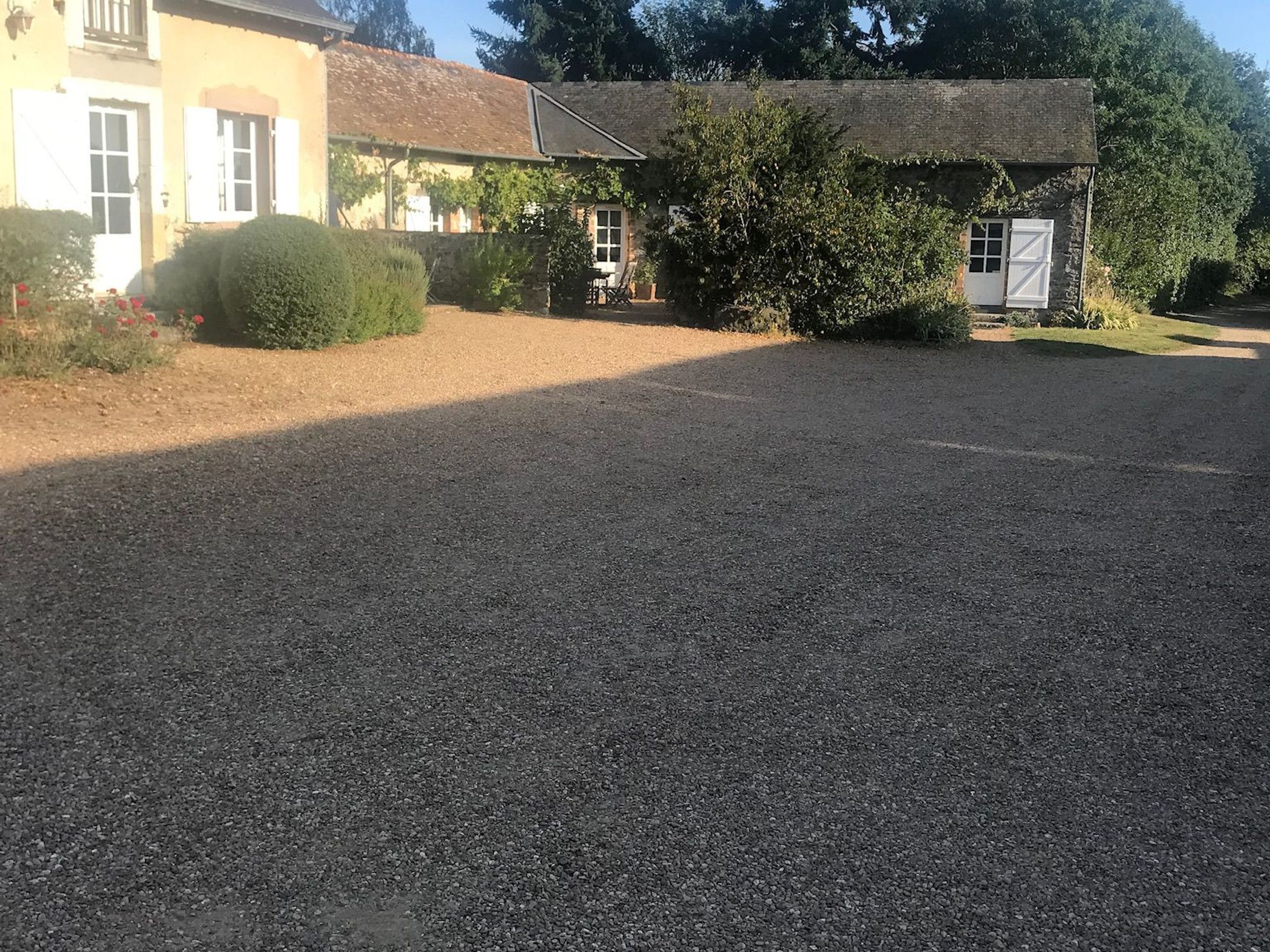 Een grindpad dat leidt naar een gebouw met een klein portaal en een deur.