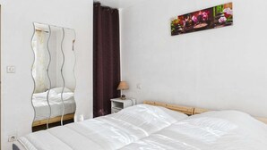 A bedroom with a bed, a nightstand, a lamp, a mirror, and a painting on the wall.