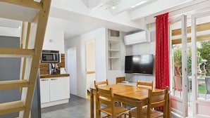 A compact kitchen with a microwave, coffee maker, and a TV. There is a dining area with a wooden table and chairs.