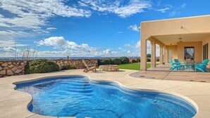 A swimming pool with a stone wall and a patio area with chairs and a table. - Las Cruces Home w/ Mountain Views & Private Pool! (Las Cruces)