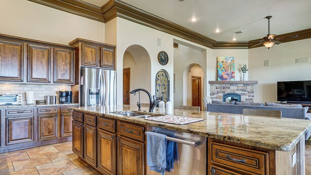 A spacious kitchen with wooden cabinets, a stainless steel refrigerator, and a granite countertop. - Las Cruces Home w/ Mountain Views & Private Pool! (Las Cruces)