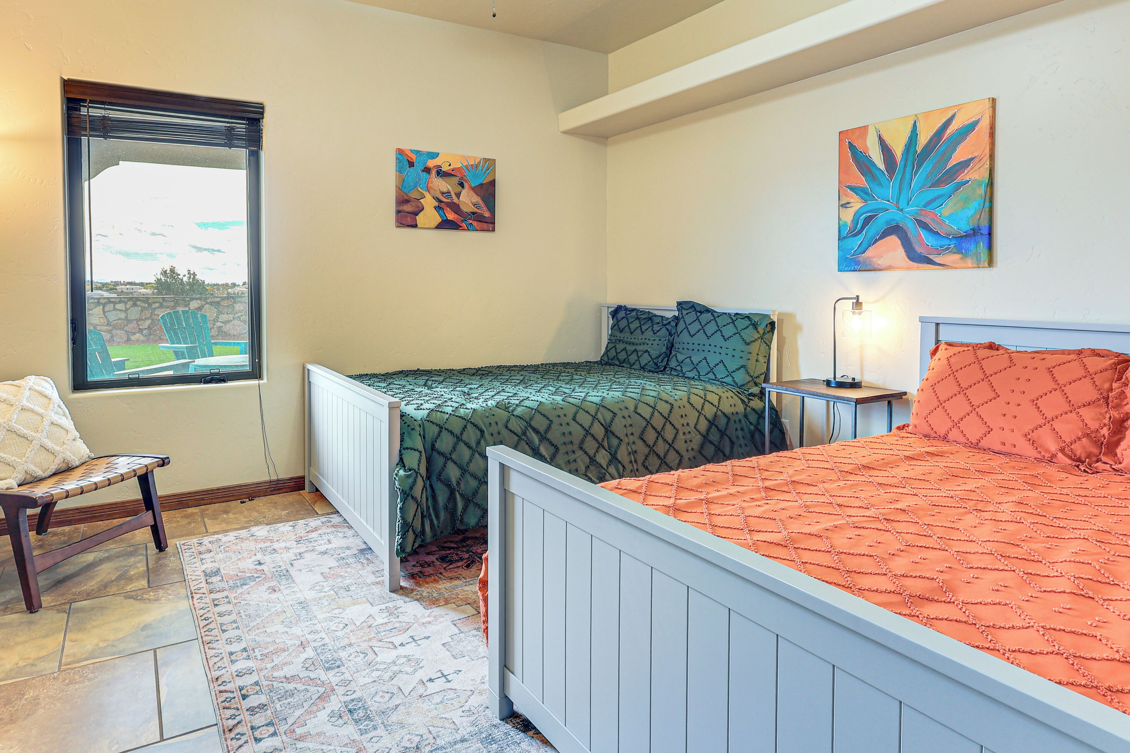 A bedroom with two beds, a window with a view, and artwork on the walls.