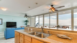A kitchen with a large window, a ceiling fan, and a view of the ocean. - Gulf Shores Beachfront Condo w/ Community Pool! (Gulf Shores)