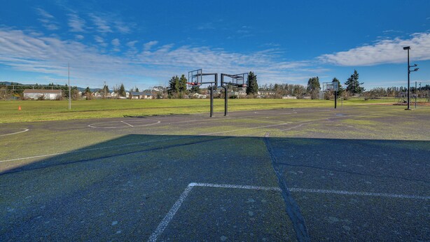En utomhusbasketplan med klar himmel och byggnader i fjärran.