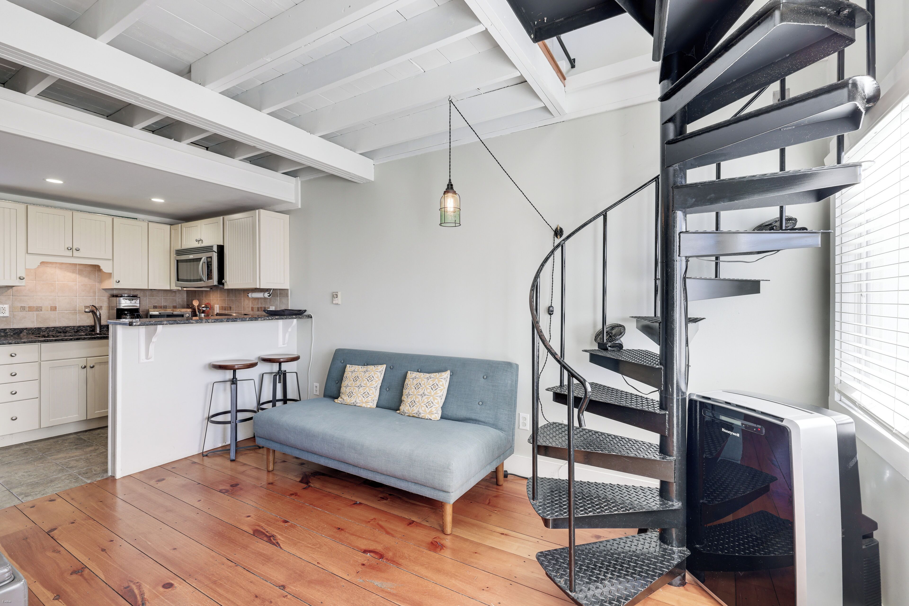 A modern kitchen with white cabinets, a built-in microwave, and a hanging light fixture.