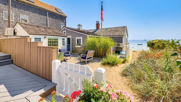 A beachfront property with a wooden deck, outdoor seating, and a view of the ocean. - Walk to Commercial Street! Couples Retreat w/ Deck (Provincetown)