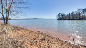 A lakeside view with a sandy shore, trees, and a clear sky. - Lake Hartwell Home w/ Dock + Fire Pit! (Townville)