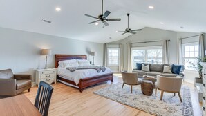 A spacious bedroom with a large bed, two ceiling fans, a sitting area with a sofa and chairs, and a dining table. - Lake Hartwell Home w/ Dock + Fire Pit! (Townville)
