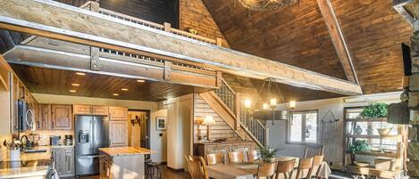 A spacious loft-style kitchen with a high ceiling, wooden beams, and a central island.