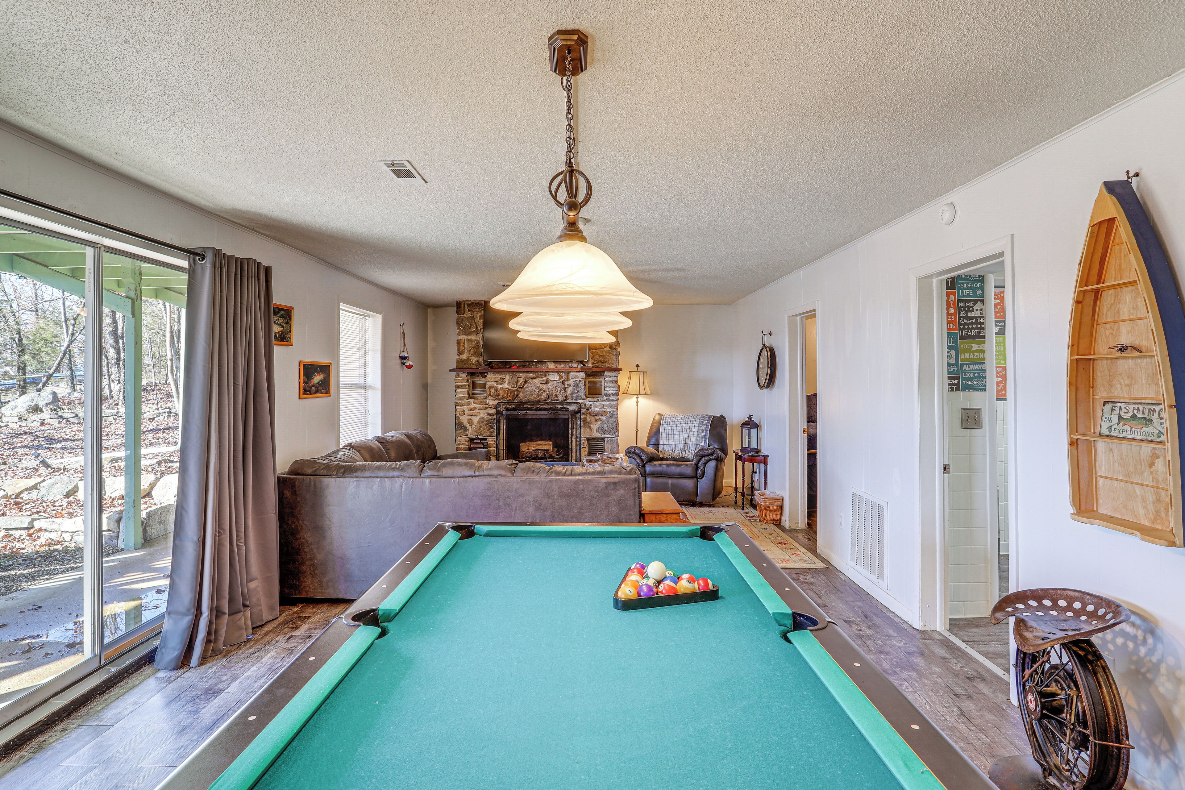 A pool table with balls, a sofa, a fireplace, and a bicycle.