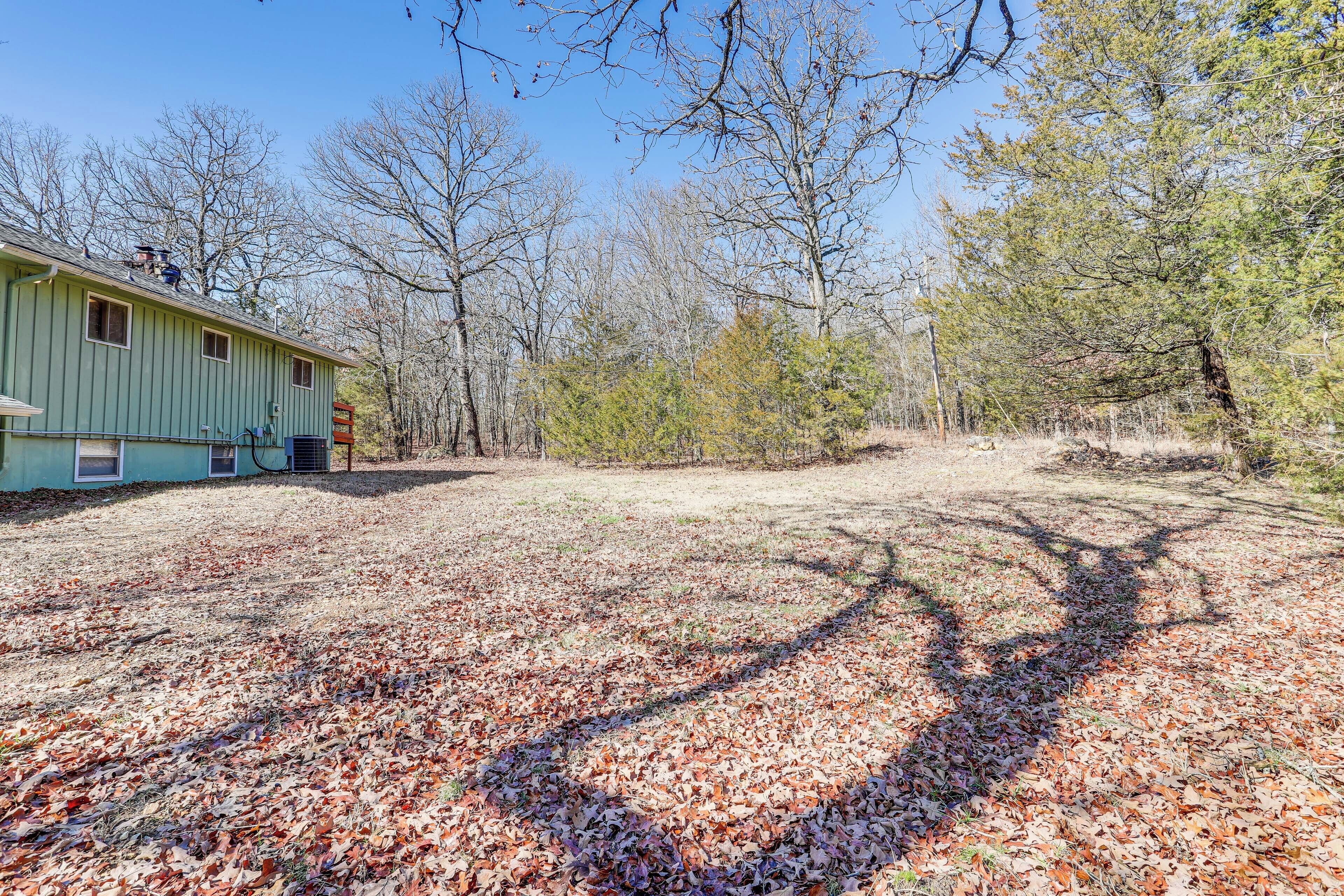 A green house with a covered porch and a yard with scattered leaves.