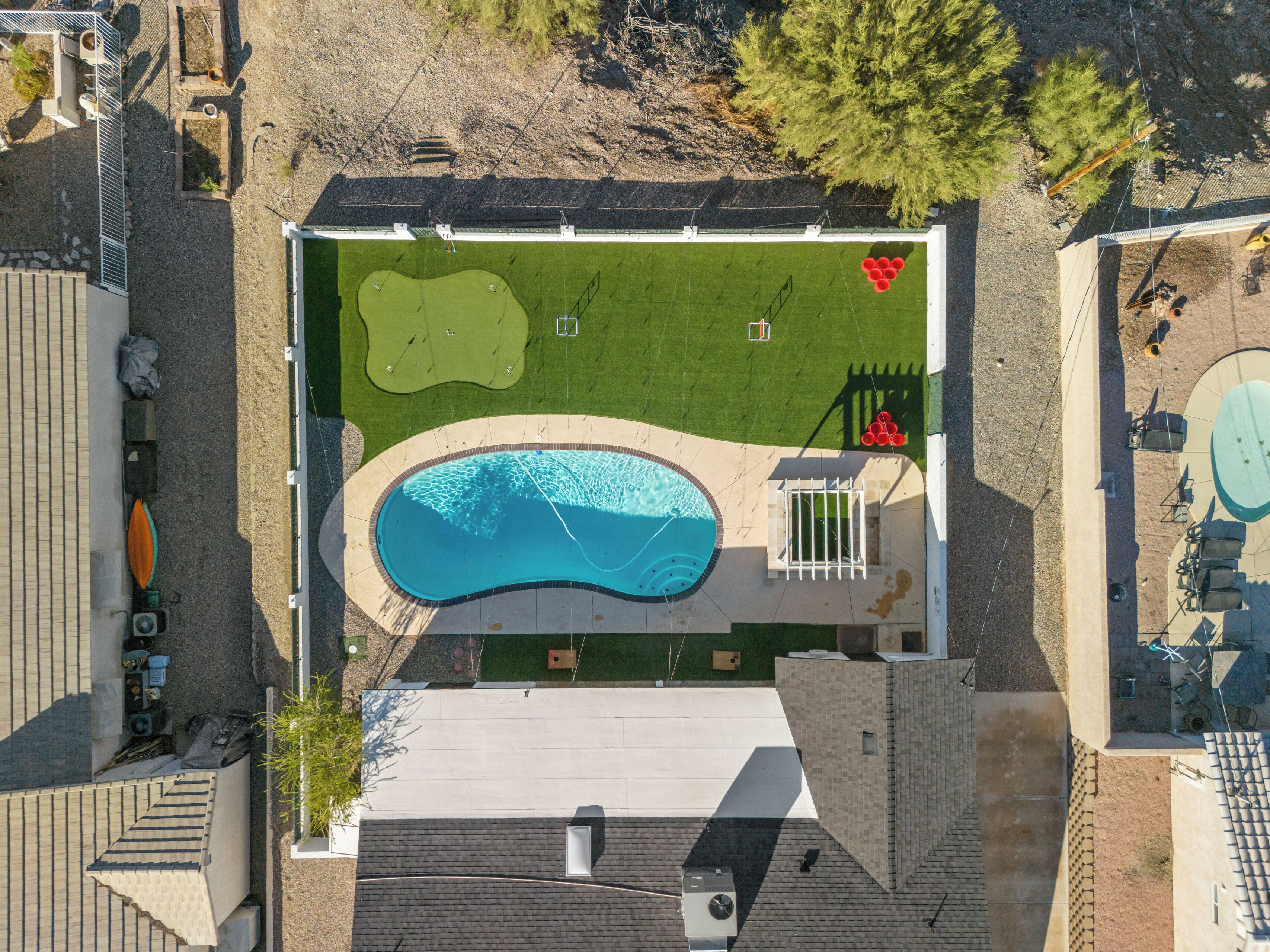 Vista aerea di una proprietà residenziale con piscina, campo da tennis e cortile recintato.