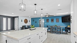 A modern kitchen with a large island, white cabinetry, and pendant lighting. - Sunny Arizona Oasis w/ Views - 2 Mi to Lake Havasu (Lake Havasu City)