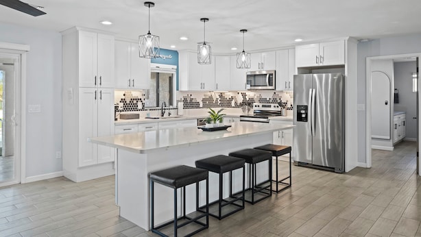 A modern kitchen with white cabinets, a central island with stools, stainless steel appliances, and pendant lighting. - Sunny Arizona Oasis w/ Views - 2 Mi to Lake Havasu (Lake Havasu City)
