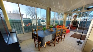 A dining area with a table set for four, surrounded by chairs, and a piano to the left.