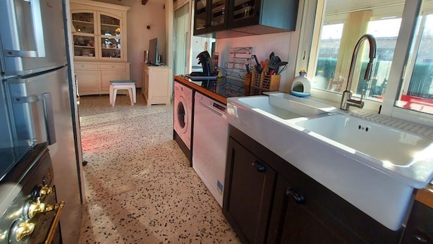 A compact kitchen with a sink, a washing machine, and a stove.