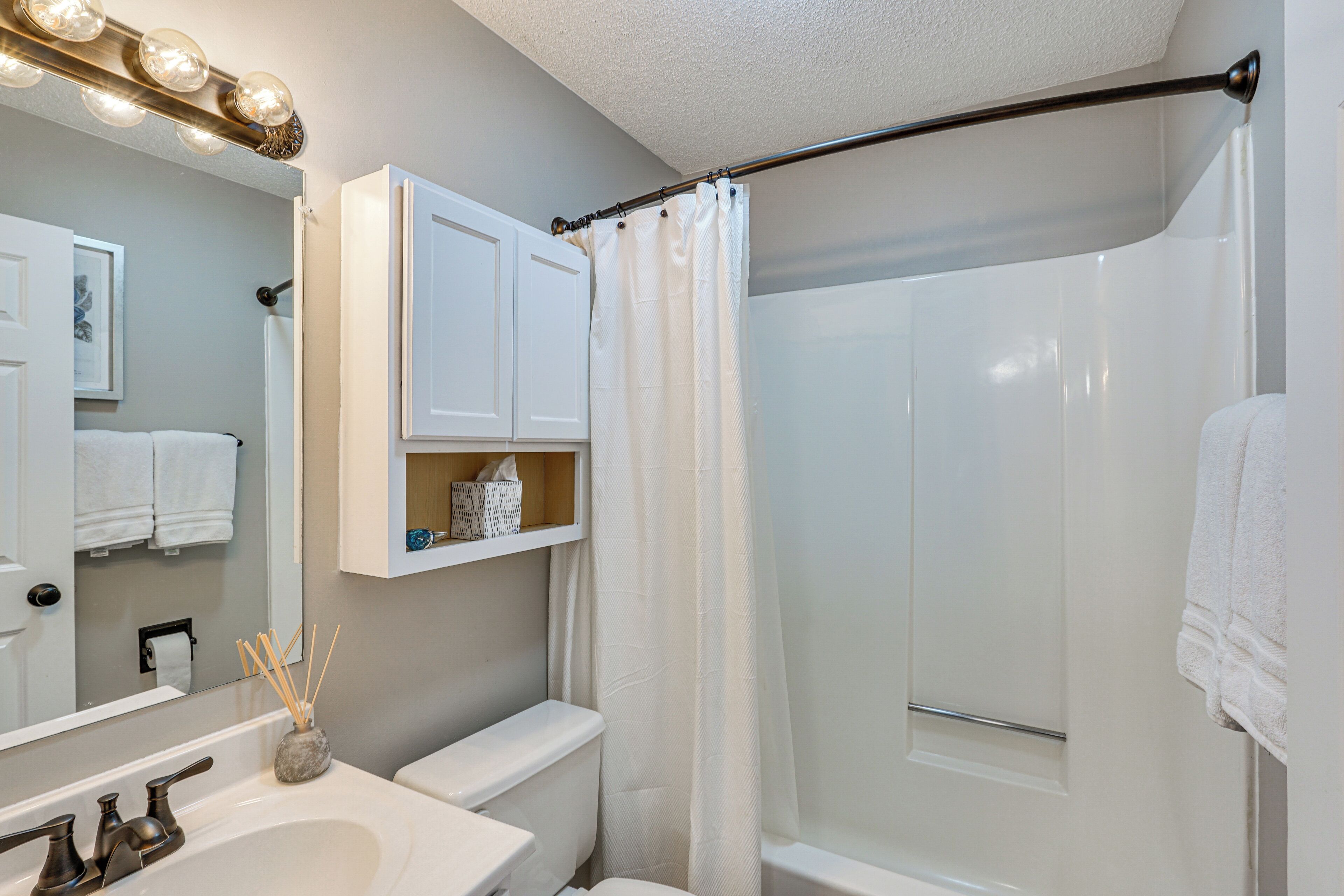 Un baño con lavamanos blanco, espejo y cortina de ducha.