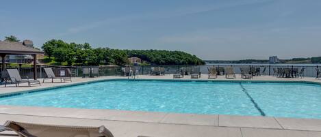 A swimming pool with lounge chairs and a view of a forested area.