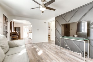 A modern living room with a ceiling fan, a glass-top table, and a sofa. - Covered Patio, Gas Grill & Yard: Sheridan Home! (Englewood)