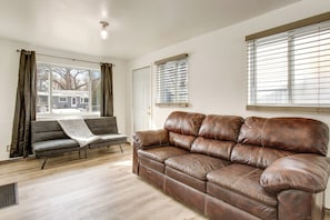A living room with a brown leather sofa, a grey sofa, and a window with blinds.