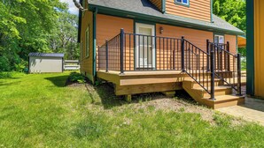 Een huis met twee verdiepingen, een houten terras en een zwarte balustrade.