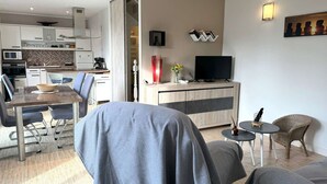 A modern living room with a dining area, a TV, and a kitchen in the background. - Seaside House with WIFI, Veranda, and Parking – 320m from the Beach in Trégastel (Trégastel)