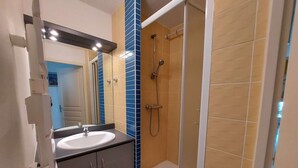 A modern bathroom with a sink, mirror, and shower. - Charming 2-Room Cabin Apartment, 50m from Beach, A/C, Parking (Marseillan-Plage)