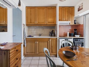 A kitchen with wooden cabinets, a dining table, chairs, a coffee maker, and a dishwasher.