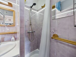 A bathroom with a shower, a sink, a mirror, and a towel rack.