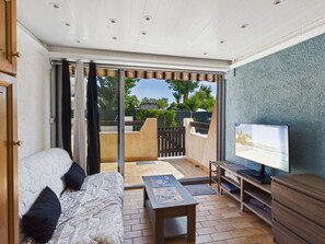 A room with a bed, a TV, and a sliding glass door leading to an outdoor area.