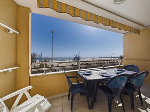 Varanda com mesa posta para dois, com vista para a praia.