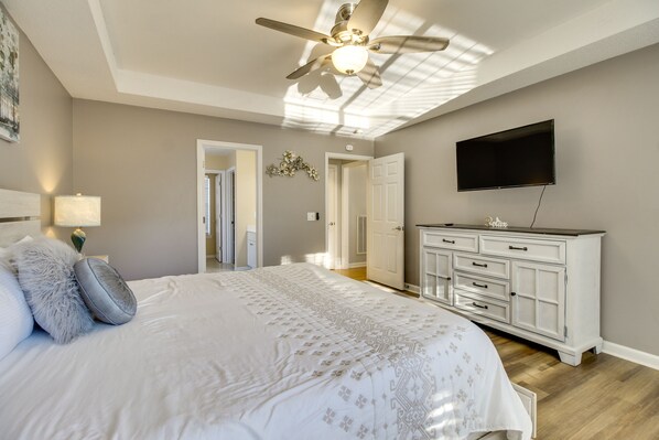 A bedroom with a bed, a ceiling fan, a TV, and a dresser.