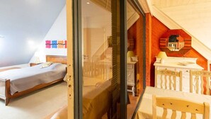 Une chambre avec un lit, un bureau et une chaise. Il y a une fenêtre et une porte.