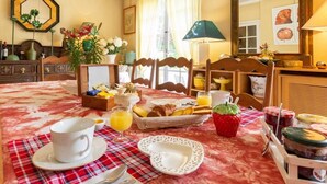 Un coin repas avec une table mise pour le petit-déjeuner, comprenant du pain, des fruits et une tasse de café.