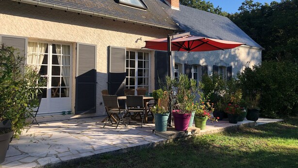 Une maison dotée d’un patio, de meubles d’extérieur et de plantes en pot.