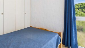 A bedroom with a bed, a wardrobe, and a window with curtains.