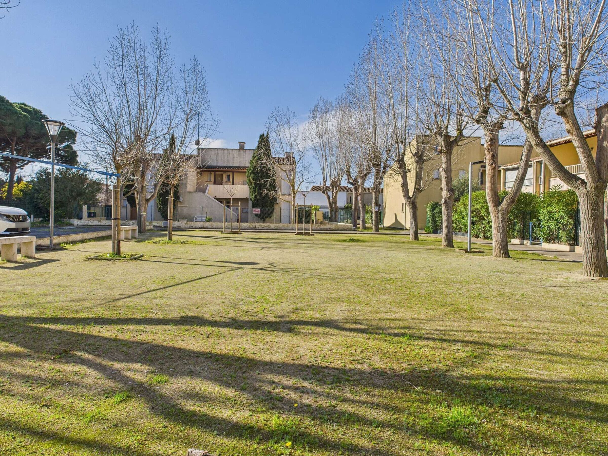 A residential area with a grassy courtyard, trees, and houses.