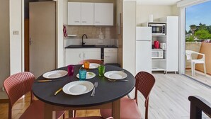 A modern kitchen with white cabinets, a dining table with chairs, and a view of the outdoors.