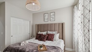 A neatly made bed with a grey blanket, a bedside table with a plant, and two framed motivational quotes on the wall. - 5br/3ba Home - King Beds - Fast Wifi 5 Bedroom Home by RedAwning (Victorville)