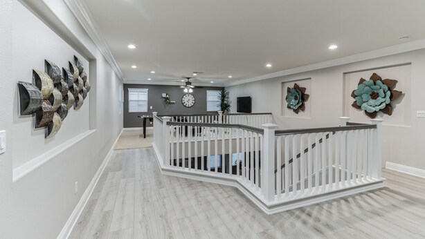 A spacious hallway with a white railing, decorative wall art, and a ceiling fan. - 5br/3ba Home - King Beds - Fast Wifi 5 Bedroom Home by RedAwning (Victorville)